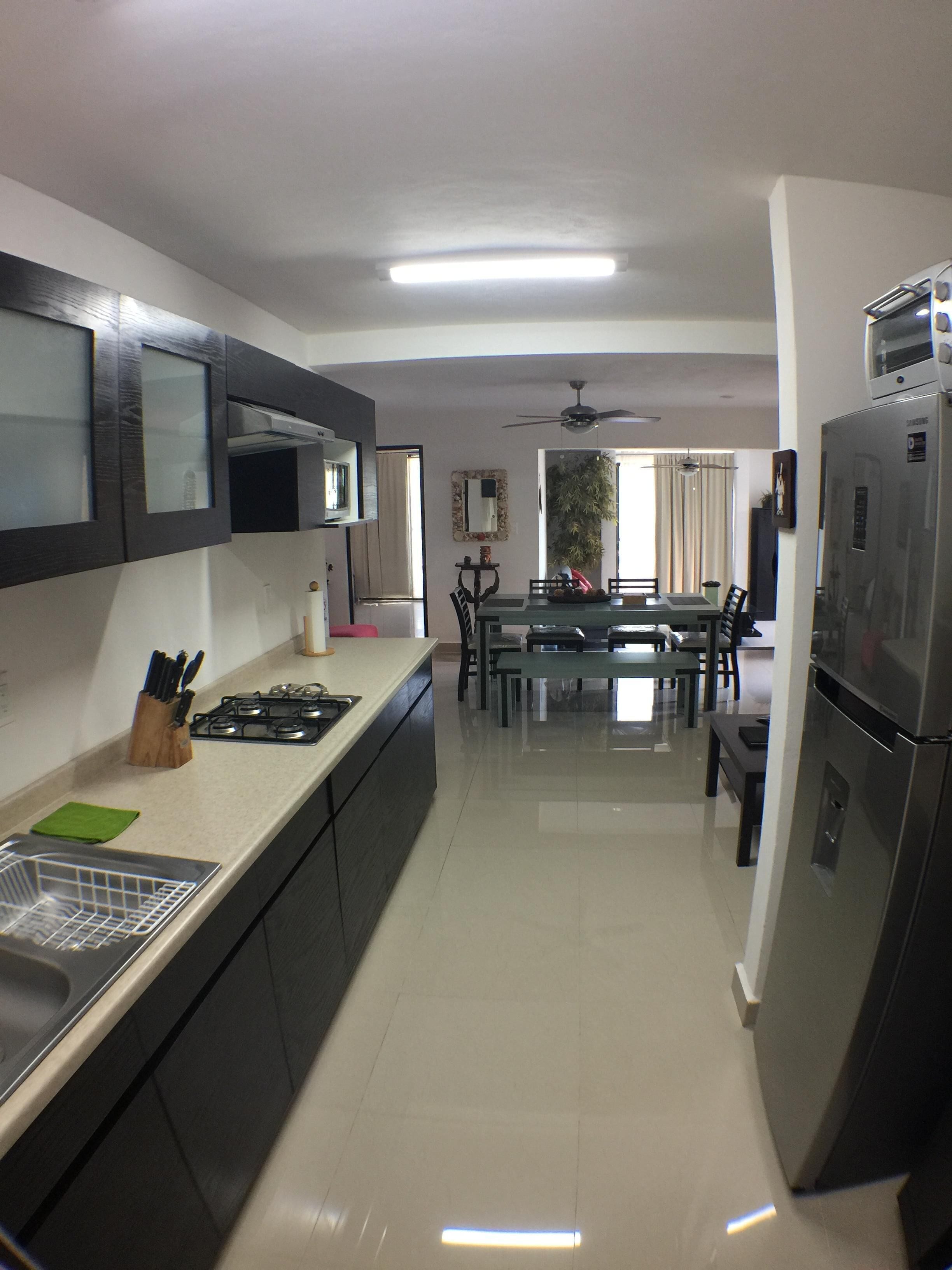 A modern kitchen with dark cabinetry, a stainless steel sink, and a built-in microwave.