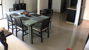 Uma sala de jantar com mesa de vidro, cadeiras pretas e ventilador de teto.