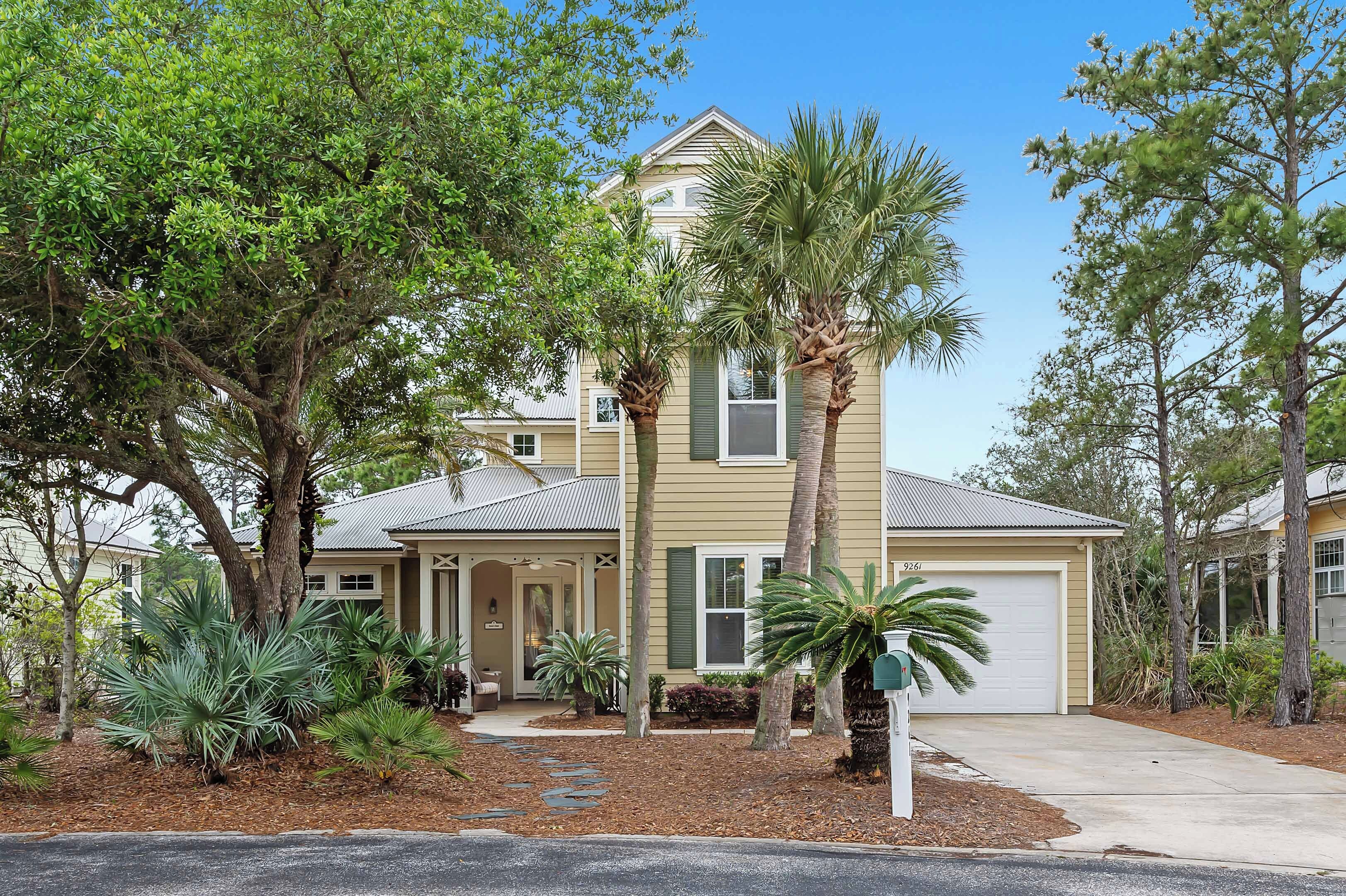 A two-story house with a covered porch, palm trees, and a mailbox.