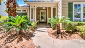 A house with a covered porch, palm trees, and a pathway leading to the entrance.