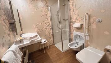 A bathroom with a shower, toilet, bidet, and sink.