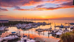 Een jachthaven met boten afgemeerd aan steigers, omgeven door rustig water en een zonsondergang.