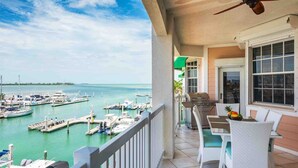 Een balkon met uitzicht op een jachthaven, een barbecue en terrasmeubels.