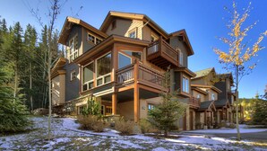 A multi-story lodge with a prominent balcony, surrounded by trees and snow. - Magnificent Townhome/Private Garage/Pool & Hot Tub Access/On the Shuttle Route! (Keystone)