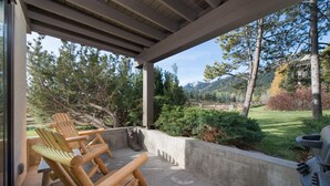 A covered outdoor area with wooden chairs and a grill. - JHRL - Nez Perce D2, Recently updated 3-bedroom Mountain Decor - 1 mile from Grand Teton NP (Teton Village)