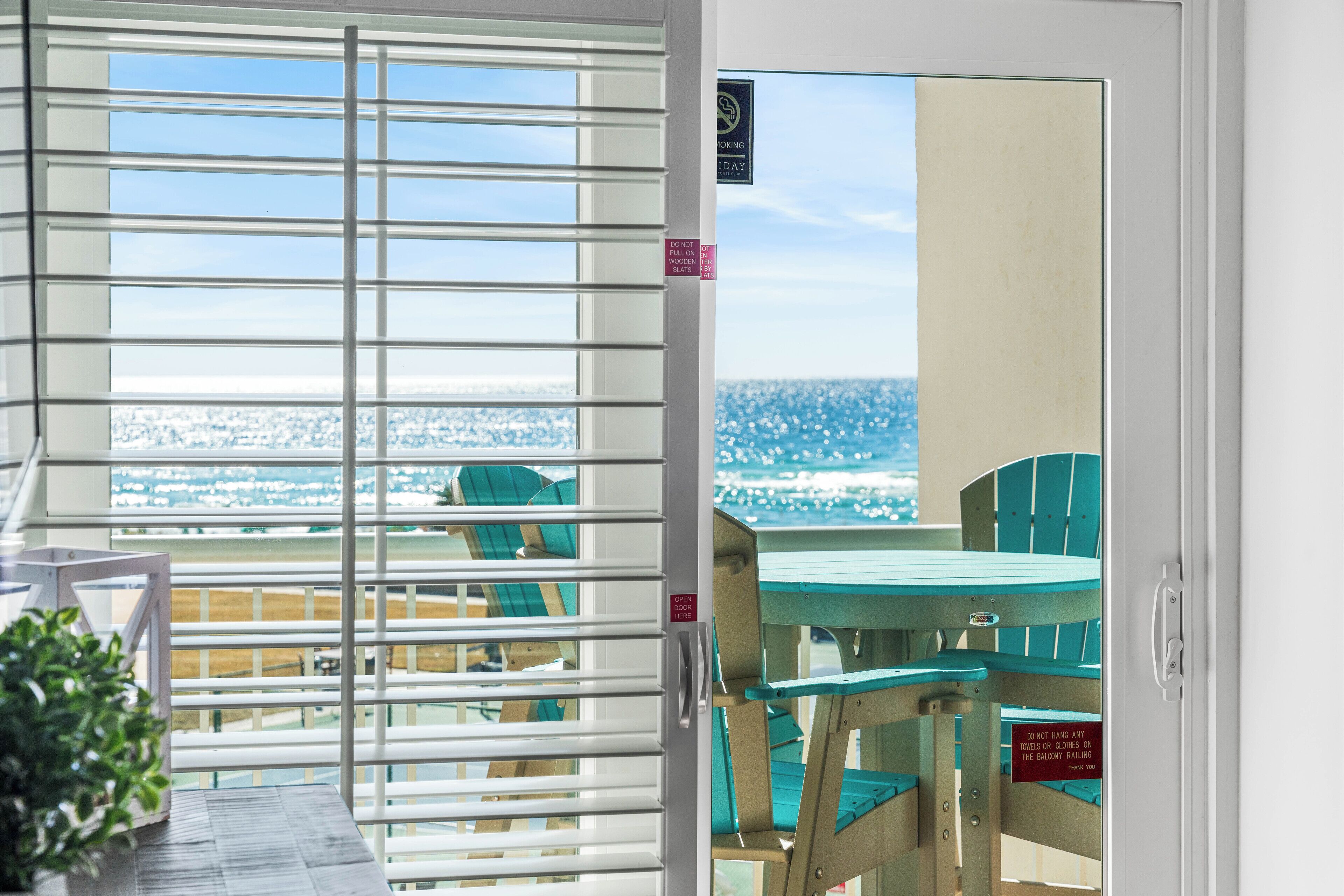 A balcony with a view of the beach and chairs.