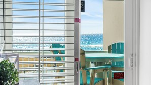 A balcony with a view of the beach and chairs.