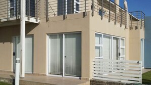 A modern building with a flat facade, large windows, and a white balcony. - Waterfront Apartment C3 (Swakopmund)