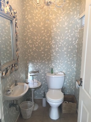 Un baño con inodoro blanco, lavamanos y espejo.
