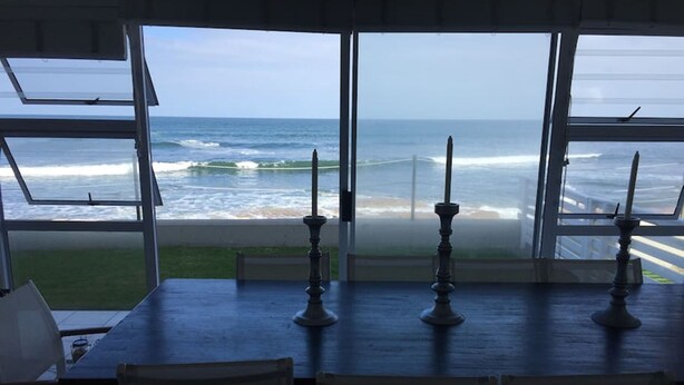 A dining area with a view of the ocean through large windows. - Waterfront Apartment C3 (Swakopmund)