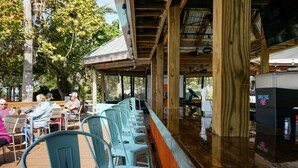 A covered outdoor seating area with rows of chairs and tables, a wooden structure with a metal roof, and a counter with a sign. - Salt Life Cottage U420 - Little Harbor Beach Resort Tampa Bay (Ruskin)