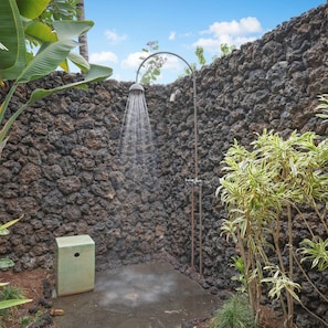 Relax in a serene outdoor oasis with a shower surrounded by lush greenery.