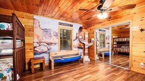 A wooden cabin interior with a bed, a bench, a floating mattress, and a large poster of the SASOUATCH TRAIL. - American themed 9BR (sleeps 43) cabin in GBurg with tons of games and space! (GATLINBURG)