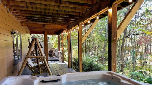 A wooden cabin with a hot tub, wooden deck, and a ladder leading to a deck chair. - American themed 9BR (sleeps 43) cabin in GBurg with tons of games and space! (GATLINBURG)