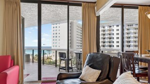 Ein Hotelzimmer mit Balkon, einem roten Sofa, einem Ledersessel und einem Esstisch.