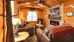 Ein gemütliches Blockhaus-Interieur mit Kamin, Ledermöbeln, einem Fernseher und rustikaler Einrichtung.