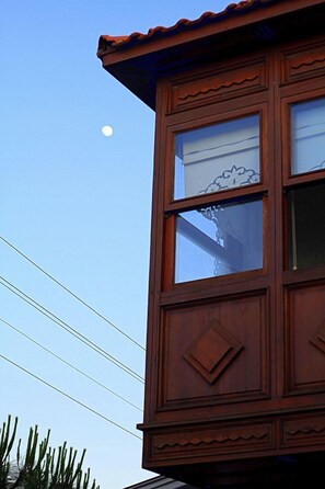 Un bâtiment en bois doté de grandes fenêtres, et une lune dans le ciel.