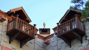 A building with two wooden balconies with intricate railings, a central decorative element, and a stone facade. - Mel'Dem Butik Otel (Cesme)