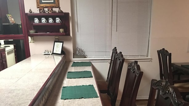 Un comedor con una mesa larga, manteles individuales verdes y sillas de madera.