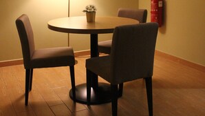 A dining area with a round table, four chairs, a lamp, a potted plant, and a fire extinguisher on the wall. - Grand Sri Lagenda (Bandar Baru Bangi)