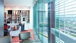 Una sala de estar moderna con una amplia estantería, un espacio de descanso acogedor y un gran ventanal con vistas a la ciudad.