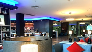 Un vestíbulo moderno con zonas de estar, una recepción y un bar.