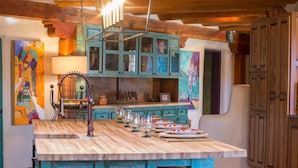 A rustic kitchen with a wooden island, teal cabinets, and a hanging light fixture.