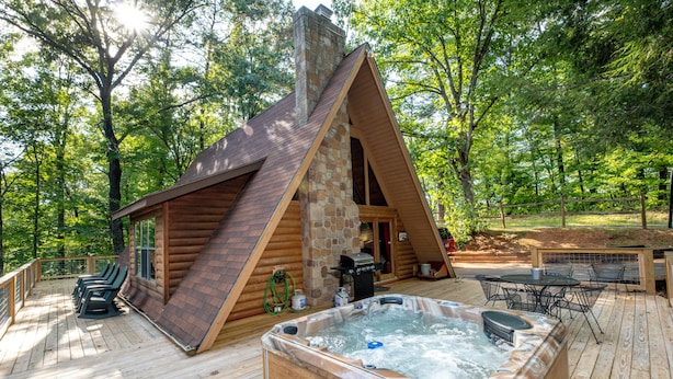 A wooden cabin with a hot tub and outdoor seating on a deck surrounded by trees. - A-Frame cabin- 3BR, pet friendly, hot tub, located between GBurg & Pigeon Forge! (Sevierville)