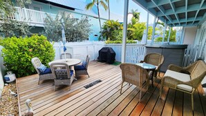 A wooden deck with wicker furniture, a grill, and a white picket fence. - Truman Annex Gem Shipyard 2BR C  Walk to Beach & Bars, Best of Old Town (Key West)
