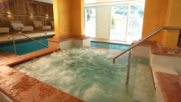 A hot tub area with a view of a pool and a wooden wall. - Ideal (Pinzolo)