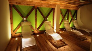 A room with wooden beams and green walls, featuring several sun loungers. - Ideal (Pinzolo)