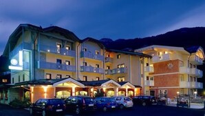 A multi-story hotel with balconies and a parking area. - Ideal (Pinzolo)