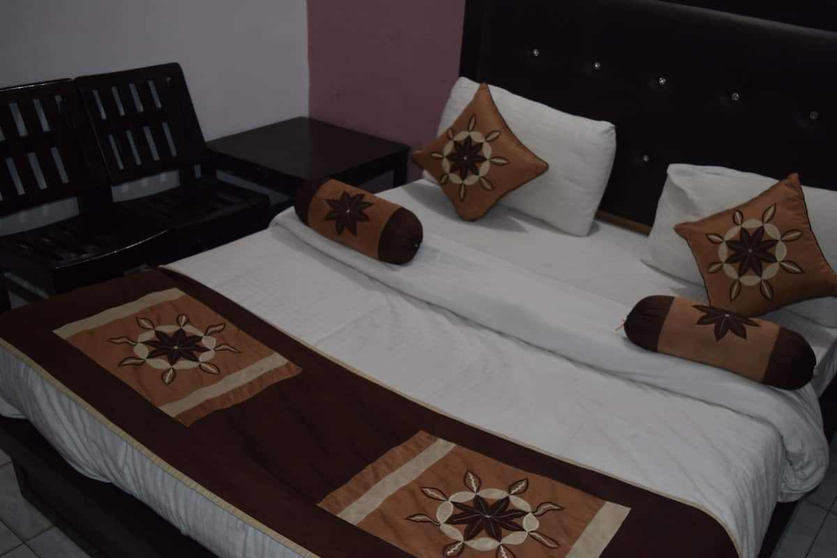 A neatly made bed with a brown and white bedspread, two pillows with a floral design, and a headboard with a tufted design.