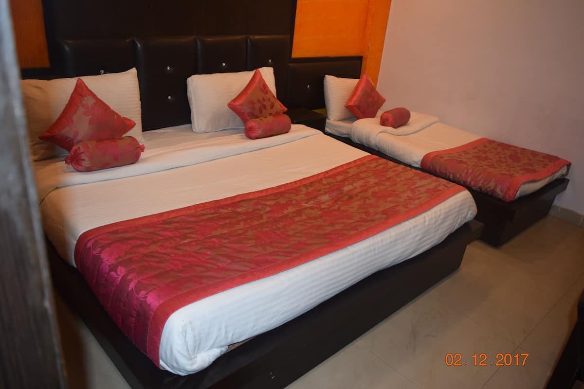 A hotel room with two beds, each with a headboard, and a red and white bedspread.