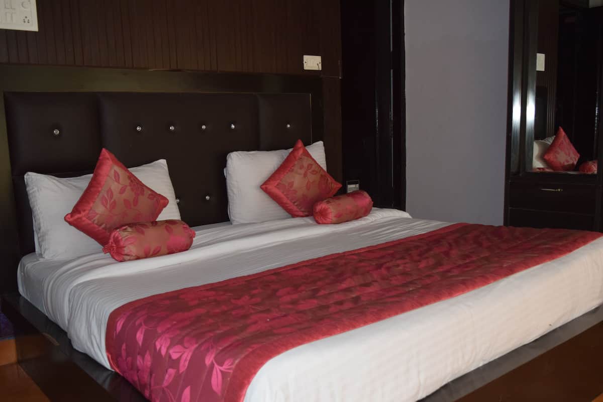 A neatly made bed with white and red bedding, a dark headboard, and a mirror on the wall.