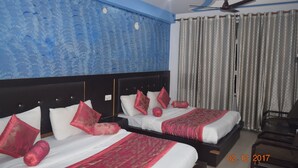 Quarto de hotel com duas camas, um ventilador de teto e uma janela com cortinas.
