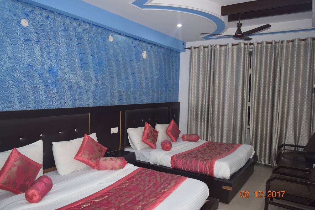 A hotel room with two beds, a ceiling fan, and a window with curtains.