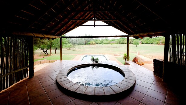 Un jacuzzi bajo un techo de madera con vista a un jardín.