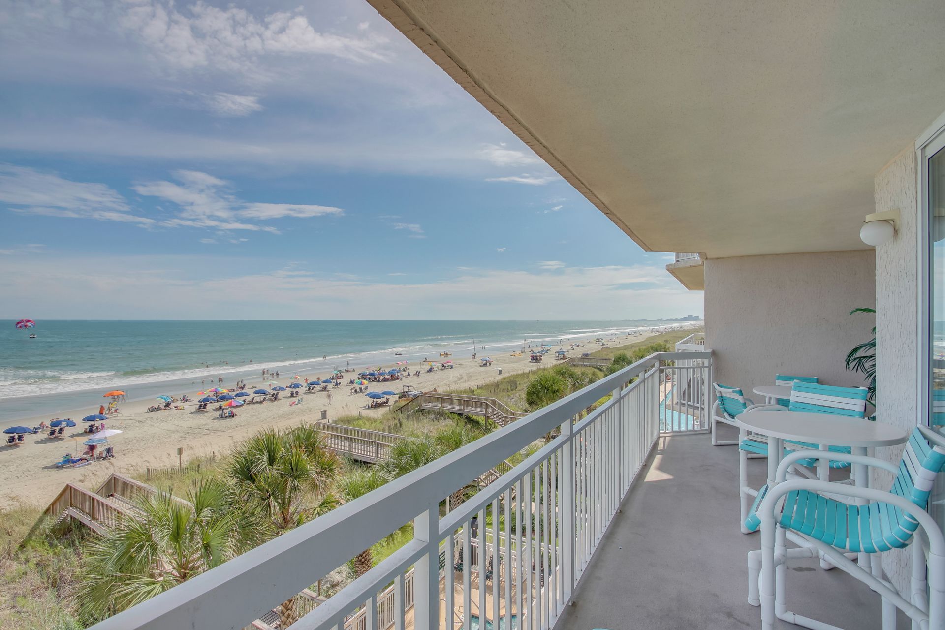 Un balcon avec vue sur la plage, un espace salon extérieur et un coin piscine.