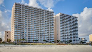 Un hotel moderno de gran altura con varios balcones, cerca de la playa.