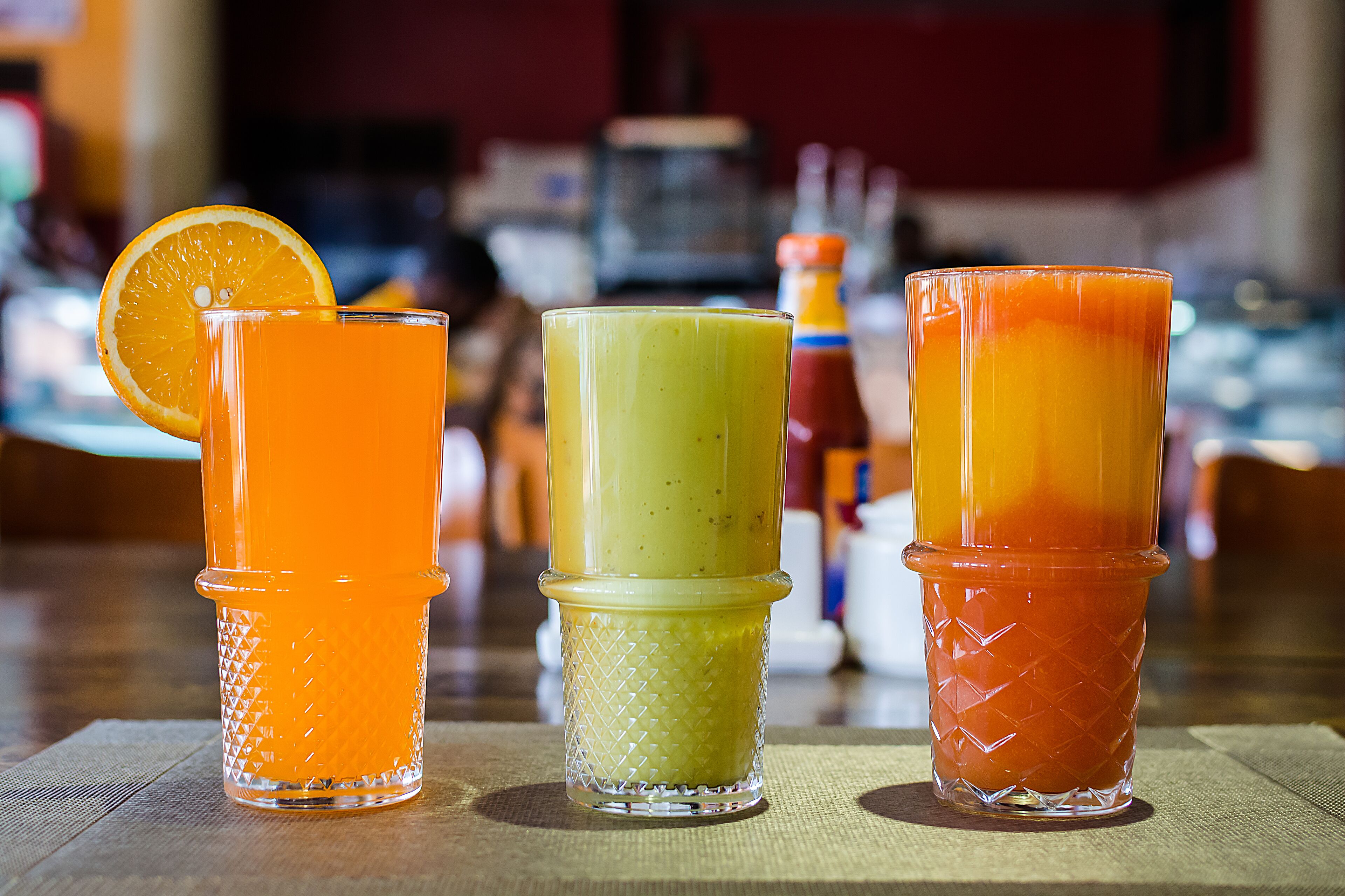 Trois verres contenant des boissons de couleurs différentes, posés sur une table.