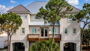 A two-story house with a front porch, a garage, and a well-maintained lawn. - Softwind |fall openings. community pool. gulf front (Dauphin Island)