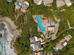 An aerial view of a resort with multiple swimming pools, a large central pool, and a beach area.