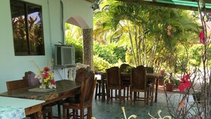 Un comedor con una mesa y sillas, un jarrón decorativo con flores, y vistas al verdor exterior.