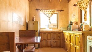 Una cocina compacta con armarios de madera, una mesa de comedor y un ventanal con cortina.