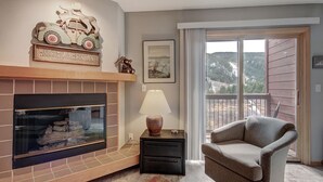 A living room with a fireplace, a sofa, a lamp, and a view of the outdoors. - Spacious Centrally Located/Short Walk to the Lifts/Hot Tub Access (Keystone)