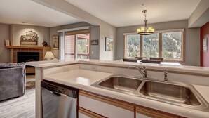 A kitchen with a double sink, wooden cabinets, and a dishwasher. There is a fireplace with a welcome sign and a chandelier above the sink. - Spacious Centrally Located/Short Walk to the Lifts/Hot Tub Access (Keystone)