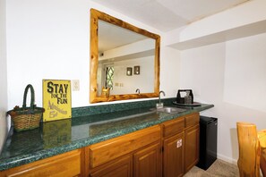 A kitchen with a granite countertop, wooden cabinets, a stainless steel sink, and a black dishwasher.