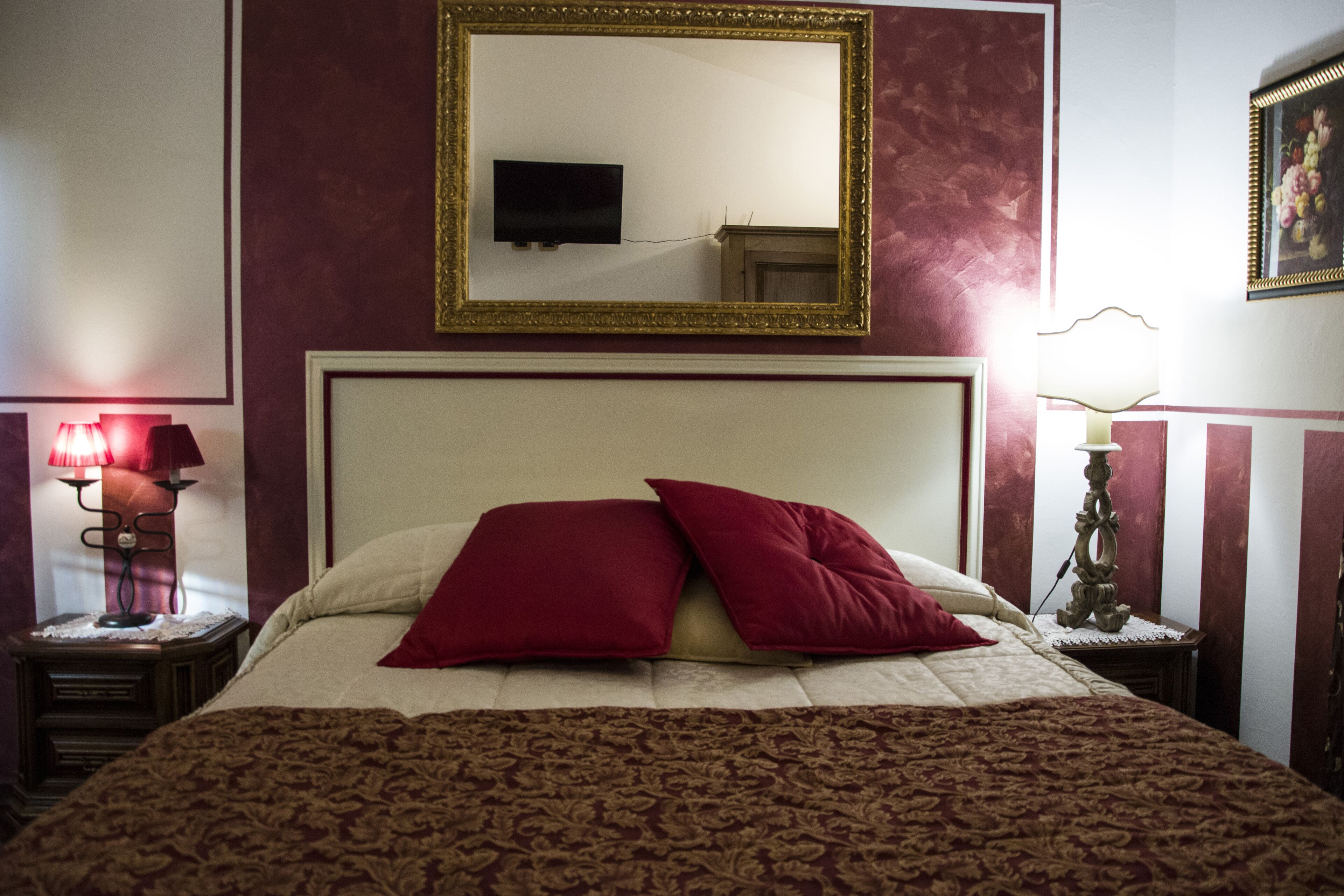 Une chambre d’hôtel avec un grand lit, un téléviseur fixé au mur et un tableau accroché au mur.