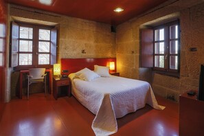 A bedroom with a large bed, a desk, and two windows. - Torre Lombarda (Allariz)